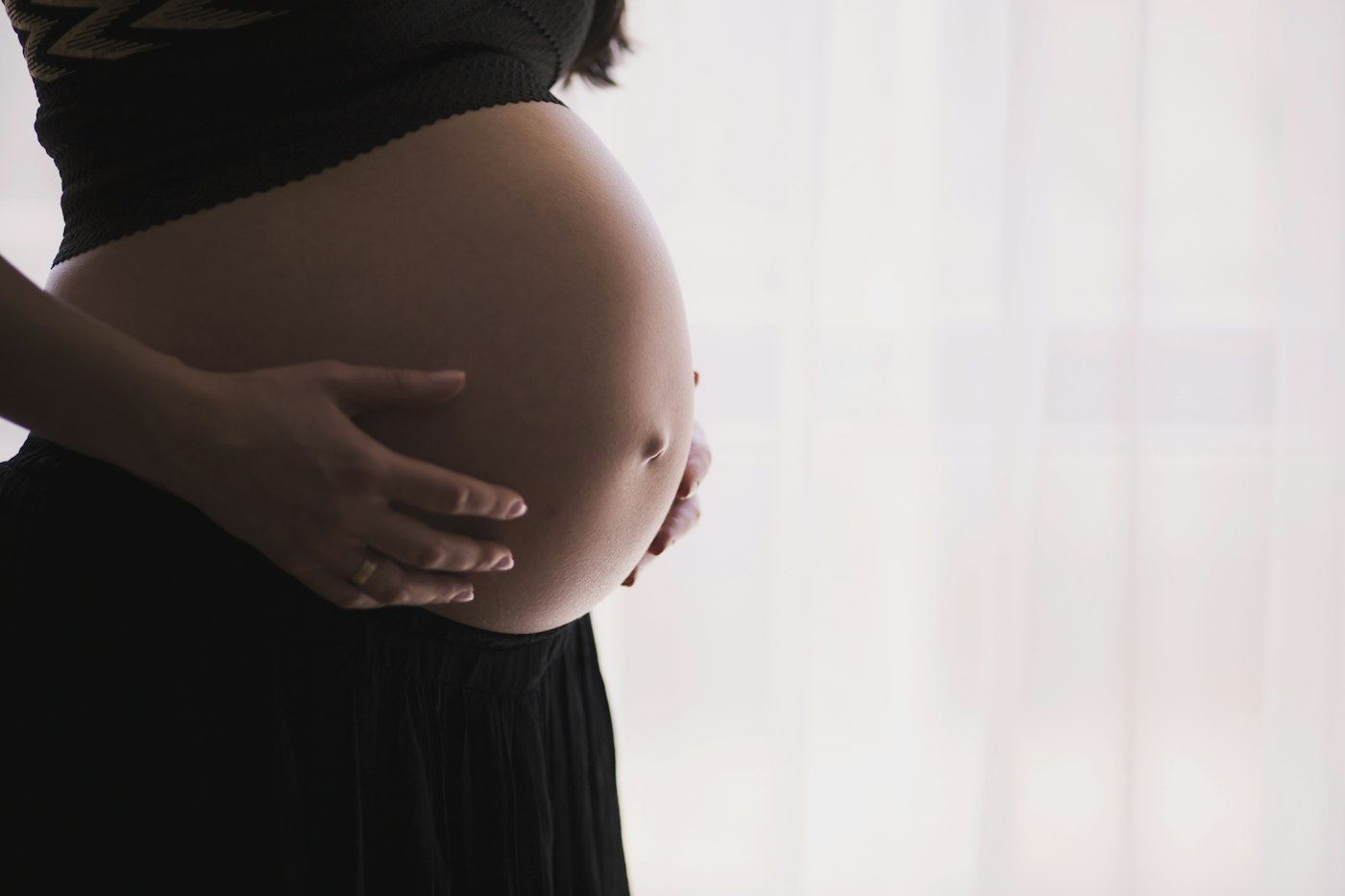 Schwangere Frau hält liebevoll ihren Bauch